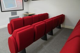 Pristine red cinema-style seating facing a screen in the school's Multimedia Centre facility.